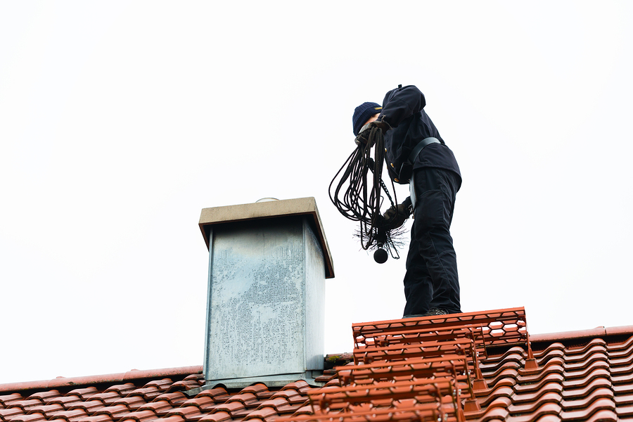 Chimney sweep standing on roof of home working